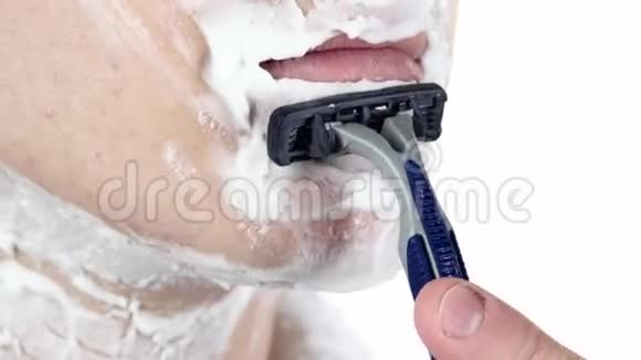 男人慢慢地剃下下巴一次性剃刀白色背景特写视频的预览图