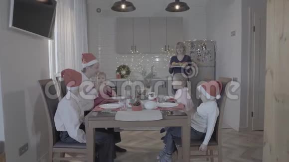 新年快乐四个孩子一家人庆祝新年厨房餐桌父亲儿子女儿微笑母亲端饭视频的预览图