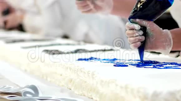 糖果组正在做一个大蛋糕奶油被应用来写铭文许多面包师在框架内视频的预览图