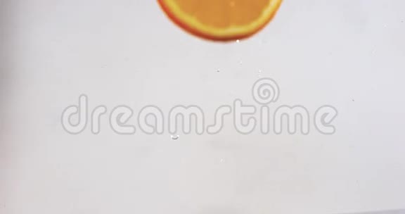 橙柑橘片落在水上溅在白色背景下视频的预览图