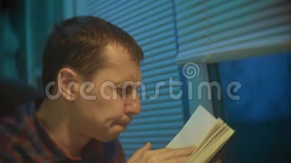 慢动作视频沉思男人晚上在窗边看书商人商人自由职业者视频的预览图