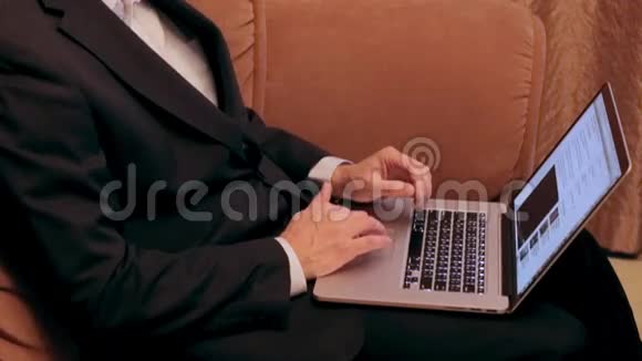 商人在家里的沙发上浏览互联网视频的预览图