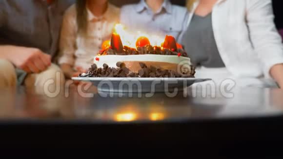 快乐的微笑男孩在她的生日蛋糕上吹蜡烛被家人包围的孩子有蜡烛的生日蛋糕视频的预览图