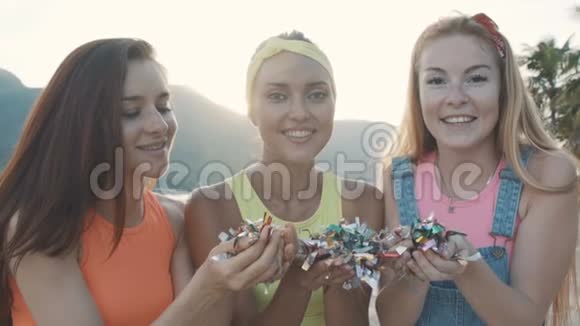 日落时分三个朋友在海滩上吹着五颜六色的闪光视频的预览图