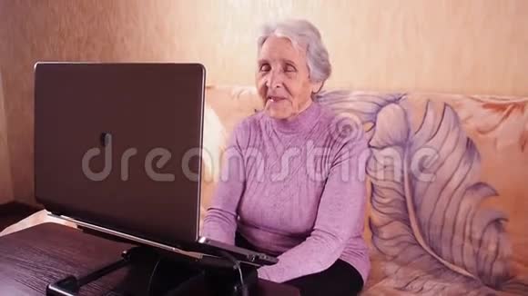 坐在沙发上用笔记本电脑打字的老年妇女金属笔记本电脑视频的预览图