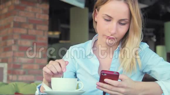 漂亮的女孩在咖啡馆里喝咖啡和用电话视频的预览图
