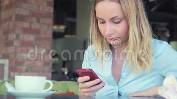 漂亮的女孩在咖啡馆里喝咖啡和用电话视频的预览图