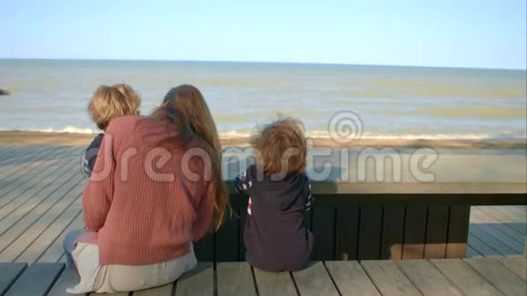 母亲和儿子坐在海边的一张桌子旁视频的预览图