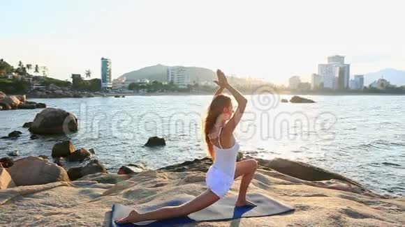 金发女郎站在洛基海滩的瑜伽体式弯曲腿上视频的预览图