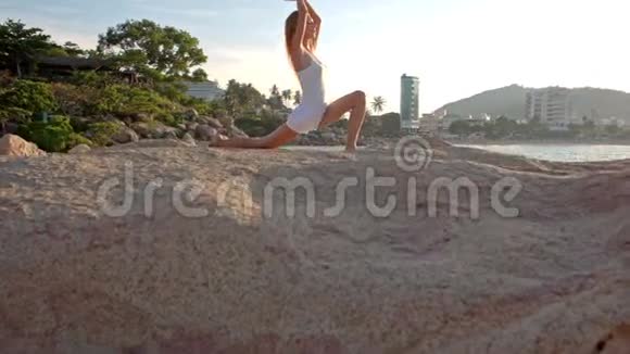 金发女郎站在洛基海滩的瑜伽体式弯曲腿上视频的预览图
