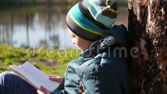 男孩在湖边的秋天公园看书美丽的秋景学校教育视频的预览图