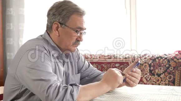 一个戴着眼镜胡子的老人在手机上拨通一条短信在家里的桌子上视频的预览图