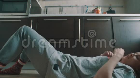 年轻的黑发女孩躺在小猫地板上坐起来抓住掉下来的玻璃视频的预览图