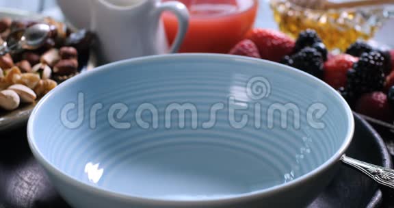 早餐谷类食物落在有浆果和干水果的碗里视频的预览图