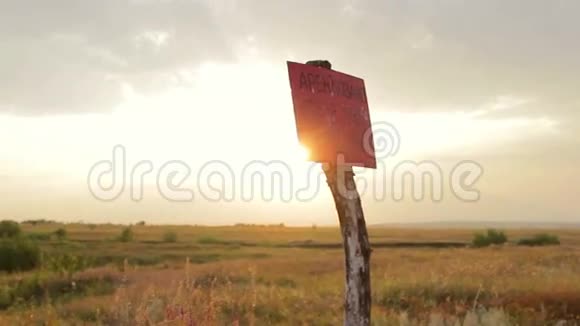 一个柱子有一个标志在日落时在田野上标记危险区域视频的预览图