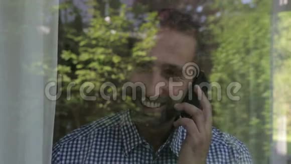 一个人站在窗户后面用他的电话视频的预览图