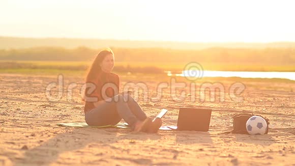 日落时分海滩上的女孩在打电话视频的预览图