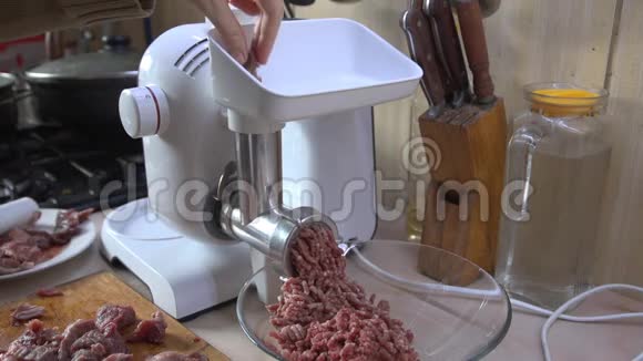 一个年轻的女人在厨房里用绞肉机做碎肉视频的预览图
