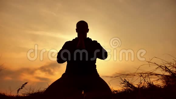 一位在日落阳光下冥想的男僧的剪影佛教祈祷日落健康生活方式视频的预览图