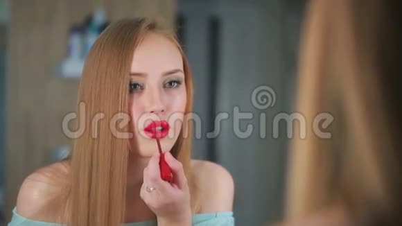 美丽的女孩看着镜子用画笔描绘她的嘴唇视频的预览图