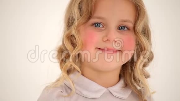 特写镜头可爱的小可爱的小女孩蹒跚学步的孩子红润的脸颊卷曲的金发在镜头中微笑视频的预览图