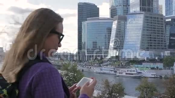 年轻女子用智能手机手机摄像头拍摄了一张高楼的照片视频的预览图