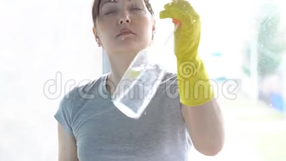 戴黄手套的女人用洗涤剂洗窗户视频的预览图