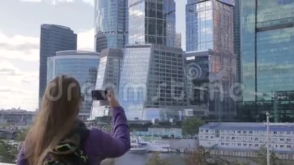 年轻女子用智能手机手机摄像头拍摄了一张高楼的照片视频的预览图