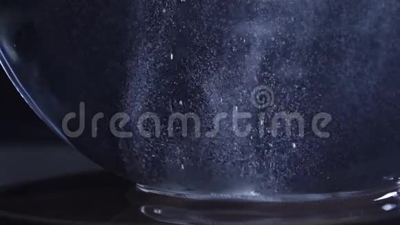 糖慢慢溶解在装有水的玻璃碗里背景很暗视频的预览图