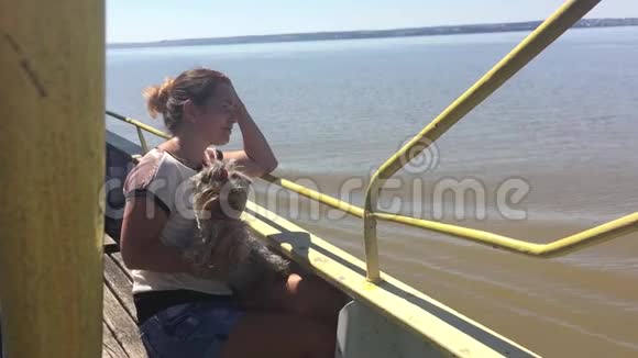 女人带着狗在船上航行在河上慢动作视频船甲板上有宠物的女孩漂浮在船上视频的预览图