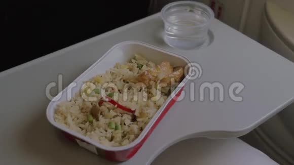 在飞机上有一个一次性餐具里面有一盘米饭和鸡肉一个女人用叉子吃食物视频的预览图