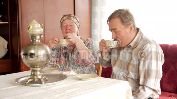 一对老夫妇正在喝一杯老式俄罗斯水壶萨莫瓦尔的茶一个留胡子的男人和他妻子在视频的预览图