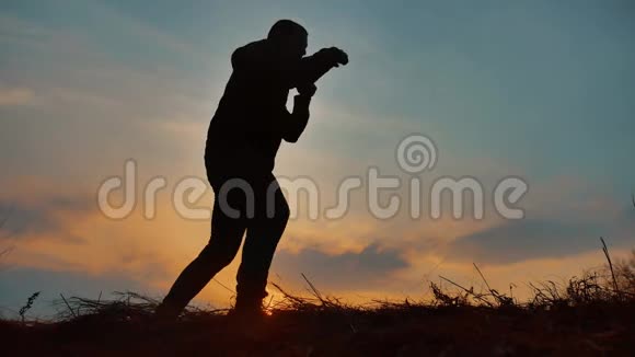 男子拳击手在自然剪影日落阳光下运动员打拳打比赛运动生活方式视频的预览图