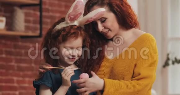 复活节快乐妈妈教女儿画鸡蛋为复活节做准备的幸福家庭他们戴着兔子耳朵视频的预览图