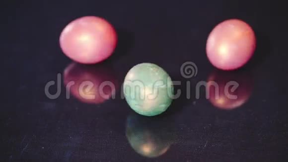 红色和绿色的复活节彩蛋在黑色背景上旋转动作缓慢视频的预览图