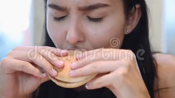 漂亮的年轻拉丁女人在室内吃汉堡包快餐视频的预览图