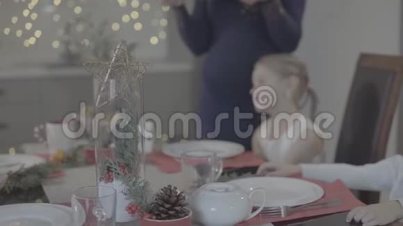 爱的母亲亲吻幸福可爱兴奋的宝贝女儿脸颊节日厨房圣诞晚餐装饰视频的预览图