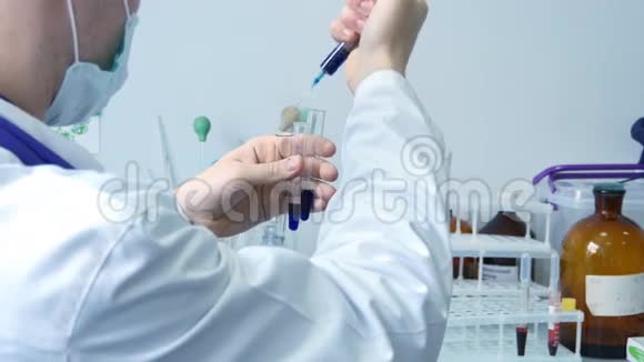 男科学家医生将化学物质注射到试管中并拿着三支蓝色物质的试管视频的预览图