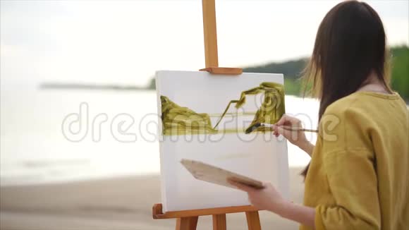 年轻女子画家在画架上画水彩画视频的预览图