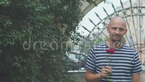 男人正在等待他的女孩与玫瑰相遇并挥动他的手愉快的会议视频的预览图