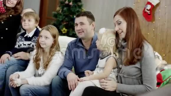 圣诞晚会上幸福的家庭坐在沙发上视频的预览图