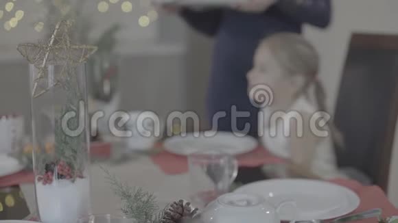 可爱的妈妈亲吻可爱的兴奋的快乐的宝贝女儿脸颊节日的厨房圣诞晚餐装饰视频的预览图