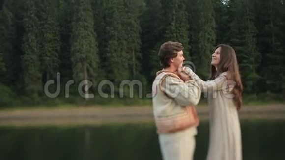 在喀尔巴阡山的森林里一对美丽的年轻夫妇穿着传统的乌克兰服装轻轻地拥抱着湖视频的预览图
