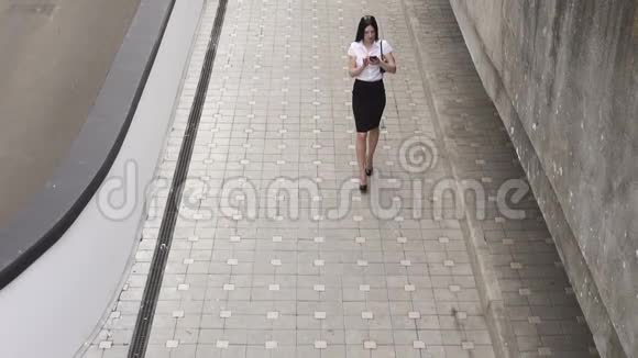 商务女性走路和使用智能手机视频的预览图