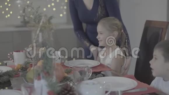 爱的母亲亲吻快乐兴奋可爱的女儿脸颊在节日的厨房圣诞晚餐装饰视频的预览图
