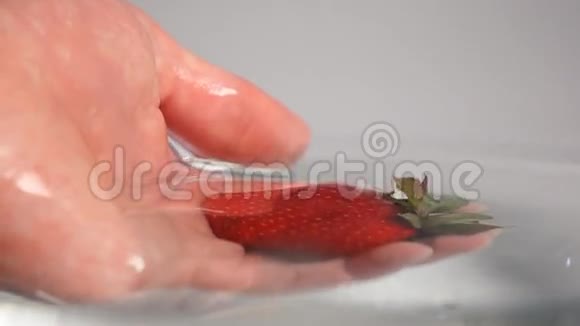 手从水中捡起草莓视频的预览图