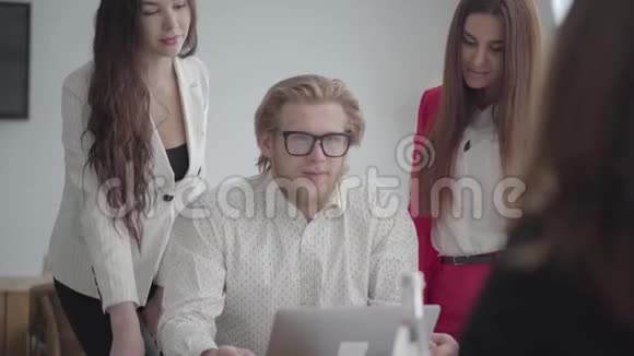 戴眼镜的金发男人坐在一间舒适的办公室里桌上放着上网本两个穿着正式服装的女孩视频的预览图