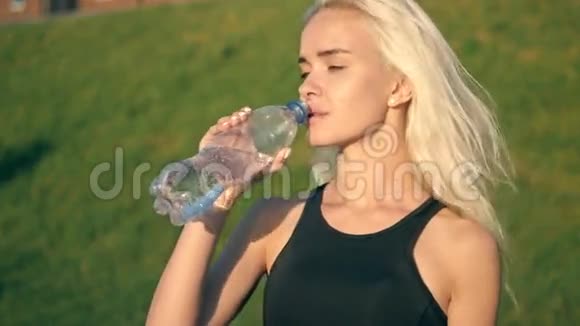 阳光明媚的日落时分运动的女人在户外喝水视频的预览图