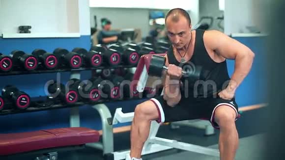 肌肉健美运动员在健身房用哑铃做运动视频的预览图