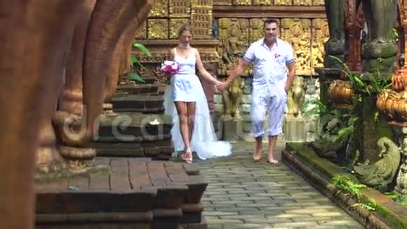 新婚夫妇漫步巴厘岛风情公园视频的预览图